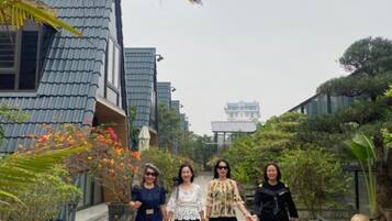 Un chemin bordé de plantes en pot et un bâtiment surmonté d’un toit en tuiles.
