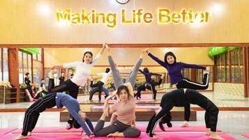 Een yogales in een ruimte met een klok en een bord waarop staat: 'Making Life Better'.