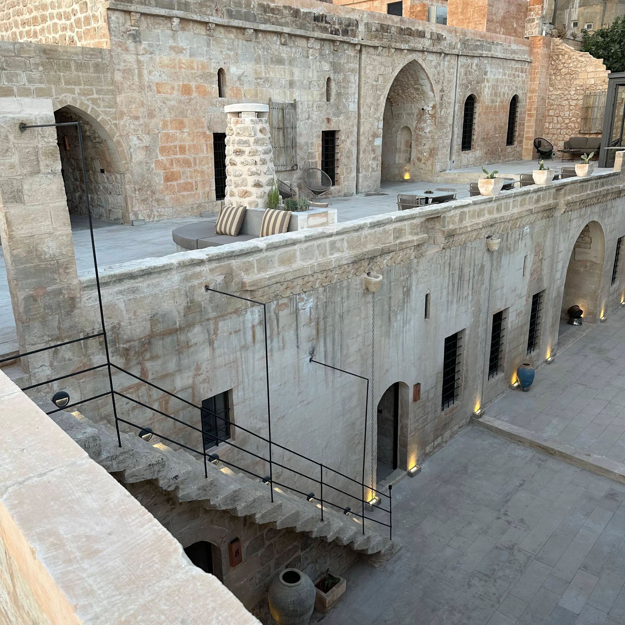A courtyard with stone walls, arched doorways, and outdoor seating.