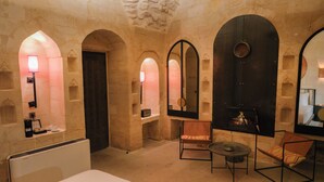 Una habitación con paredes de piedra, una chimenea, una cama, una silla y una mesa.