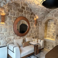 A stone-walled room with a round mirror, two sofas, and a small table.