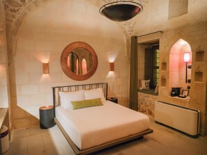 Un dormitorio con cama, mesita de noche, lámpara y espejo.