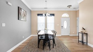 A dining area with a wooden table and chairs, a patterned rug, and a door with a decorative arch.