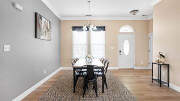 Un comedor con una mesa y sillas de madera, un tapete estampado y una puerta con un arco decorativo.
