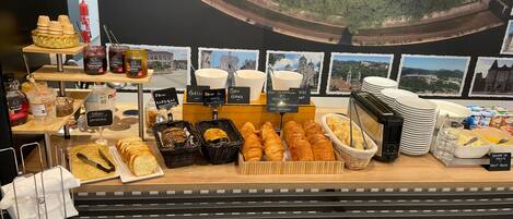 Een ontbijtbuffet met diverse gerechten en een prachtig uitzicht over een kustplaats.