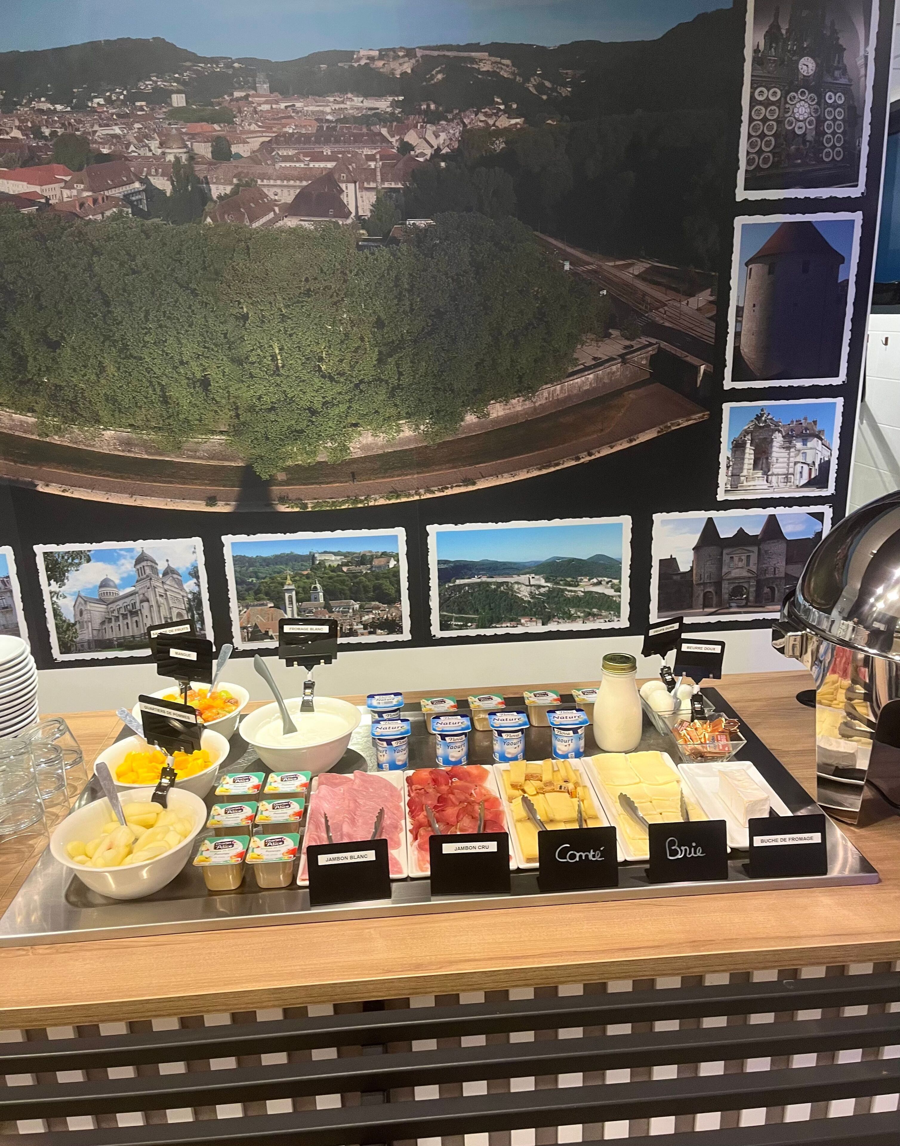 Ein reichhaltiges Frühstücksbuffet mit ausgeschilderten Speisen und einem malerischen Blick auf die Stadt.