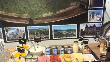 Un bufé de desayuno con alimentos identificados y un hermoso panorama de un pueblo.