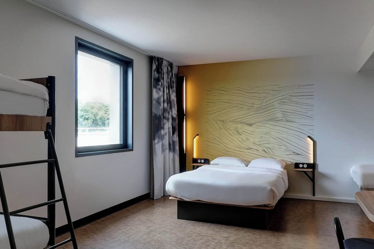 Ein modernes Hotelzimmer mit einem großen Bett, einem Schreibtisch, einem Sessel, einer Hockerleiter, einem Fenster und einem außergewöhnlichen Wanddesign.