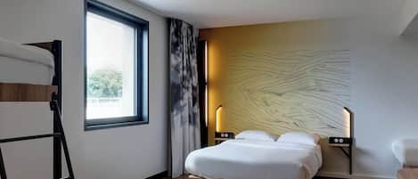 A modern hotel room with a large bed, a desk, a chair, a ladder, a window, and a unique wall design.