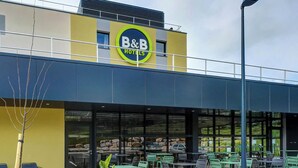 A B&B hotel with outdoor seating and a stone wall. - B&B HOTEL Besançon Valentin (Miserey-Salines)