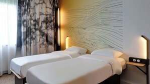 A hotel room with two beds, a large abstract wall art, a nightstand with a lamp, and a view of the outdoors through sheer curtains. - B&B HOTEL Besançon Valentin (Miserey-Salines)