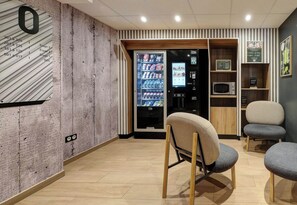 A modern interior with a vending machine, seating area, and a wall with a large number '0'.