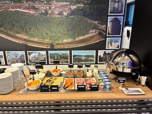 A buffet with various food items and a view of a town in the background.