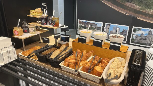 A breakfast buffet with various bread, pastries, and cereal options. - B&B HOTEL Besançon Valentin (Miserey-Salines)