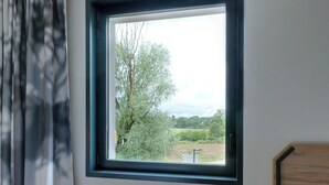 A window with a view of trees and a field. - B&B HOTEL Besançon Valentin (Miserey-Salines)