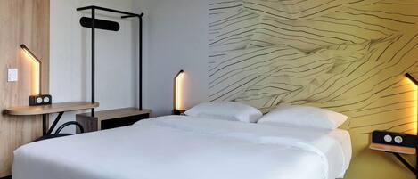 Una habitación de hotel moderna con una cama grande, una mesita de noche con lámpara, una luz empotrada en la pared y un diseño de pared texturizado único.