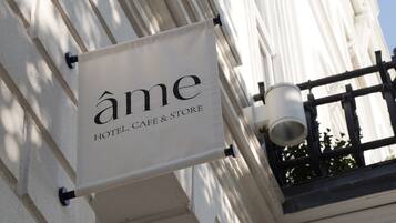 A sign for 'Ame Hotel, Café & Store' mounted on a building with classical architectural details.
