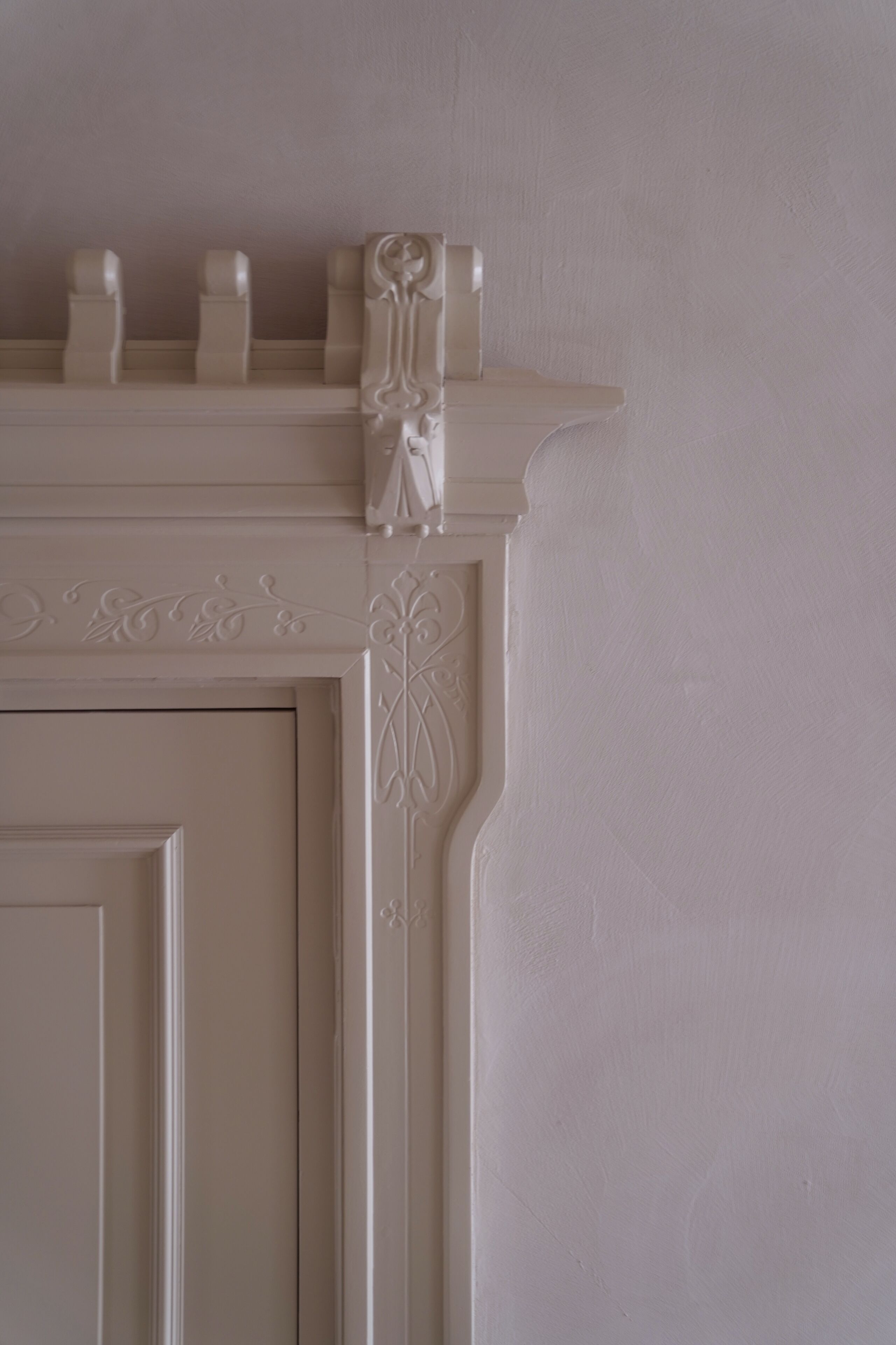 A white, ornate fireplace mantel with decorative moldings and a small statue.