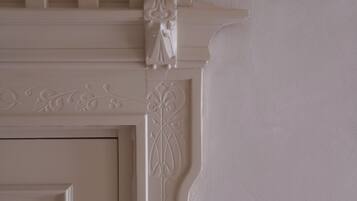 A white, ornate fireplace mantel with decorative moldings and a small statue.