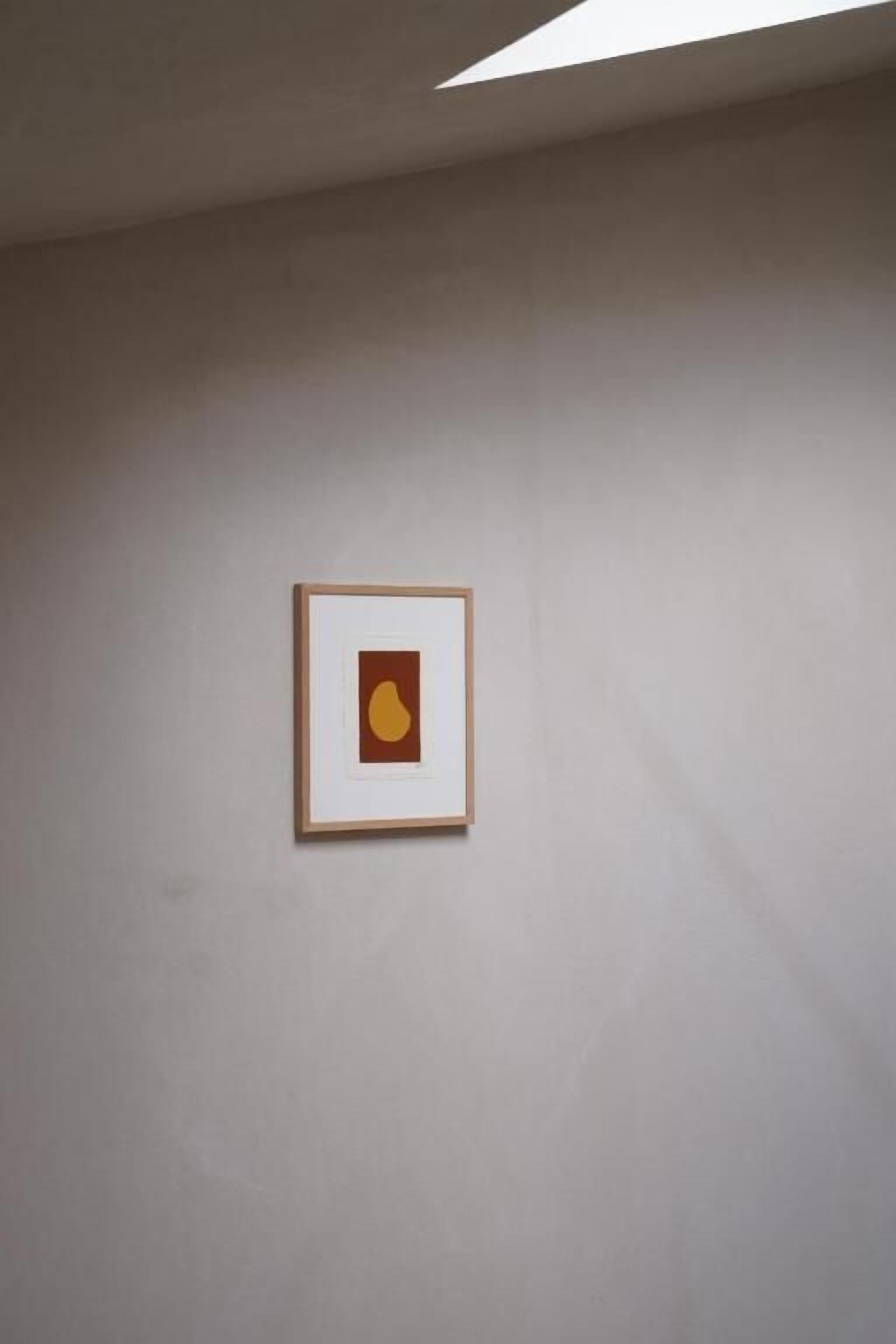 Une œuvre d’art encadrée accrochée à un mur uni.