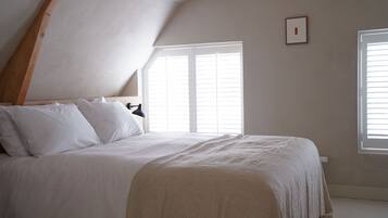 A bedroom with a bed, two windows, and a sloped ceiling.