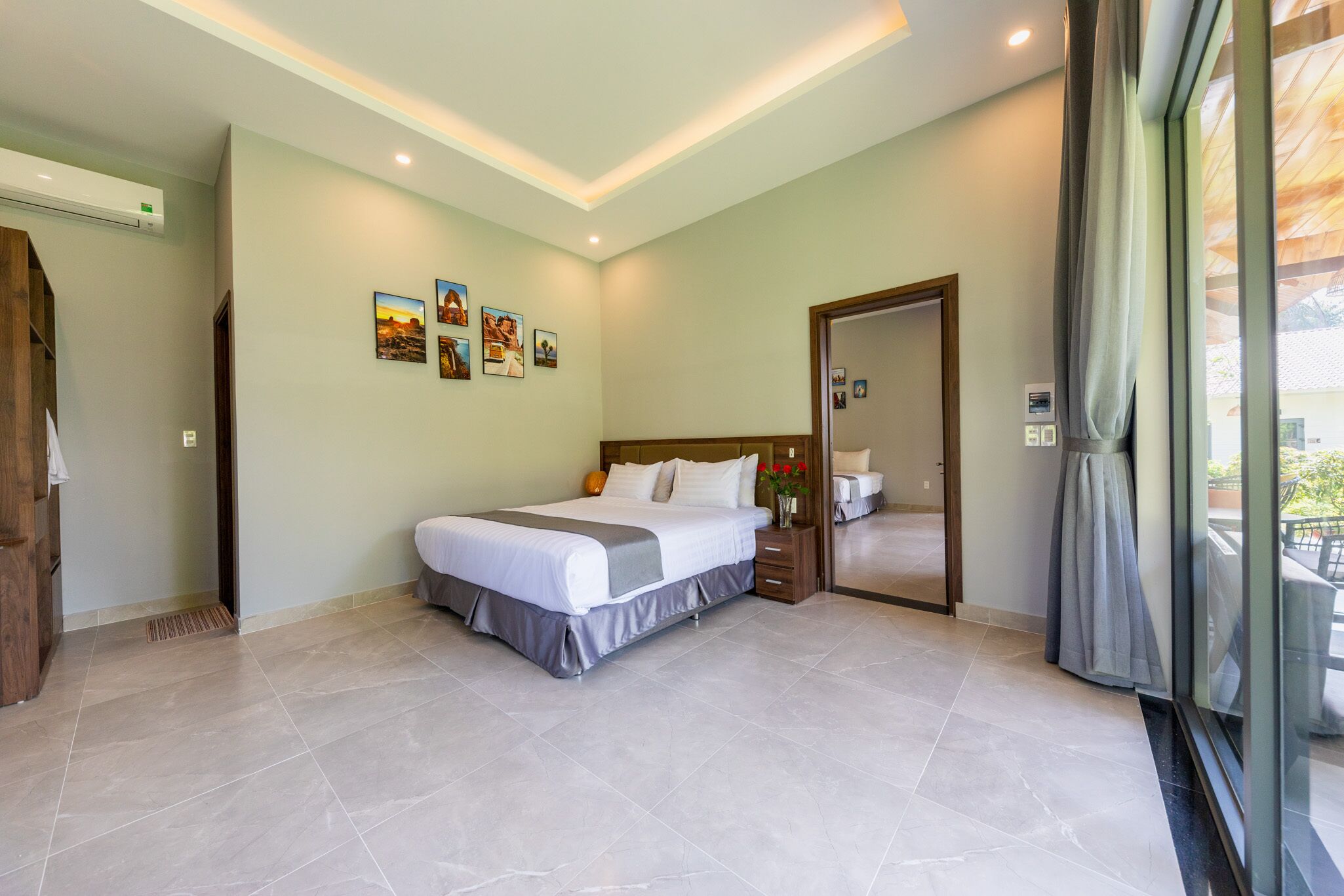 A hotel room with a large bed, a bedside table, a mirror, and a window with curtains.