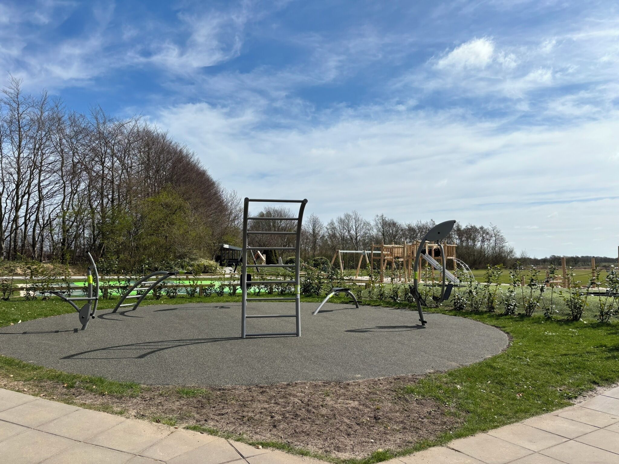A playground with a metal climbing structure, swings, and a slide.