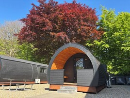 Um edifício moderno em estilo de cabana, com arco, interior de madeira e entrada por um caminho de brita.