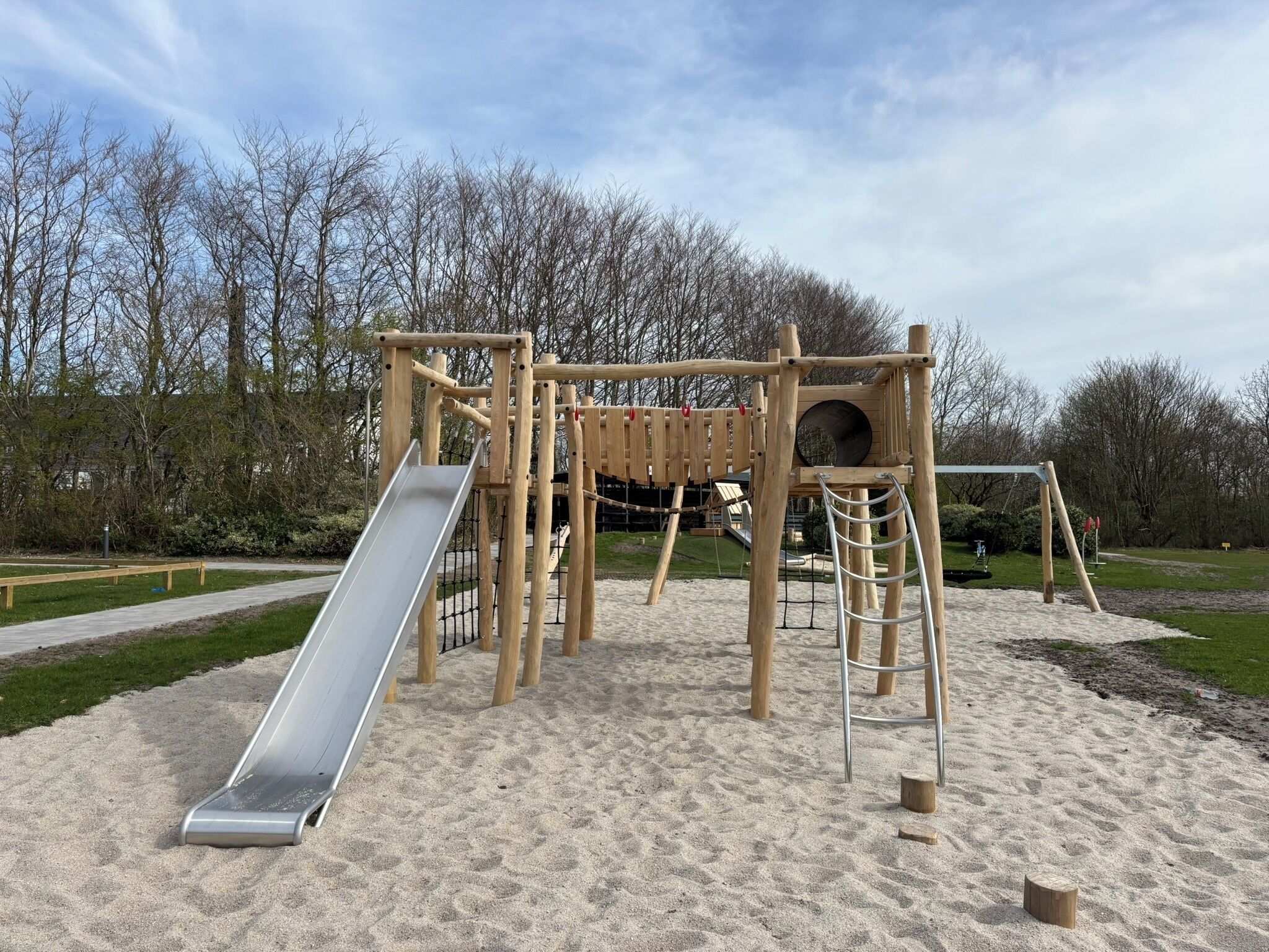 A playground with a slide, climbing structures, and a sandpit.