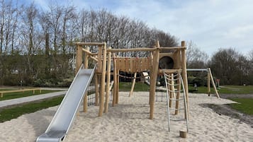 A playground with a slide, climbing structures, and a sandpit.