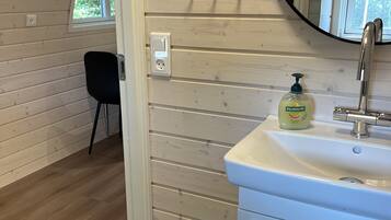 Un baño con lavamanos blanco, un espejo y una botella de jabón Palmolive.