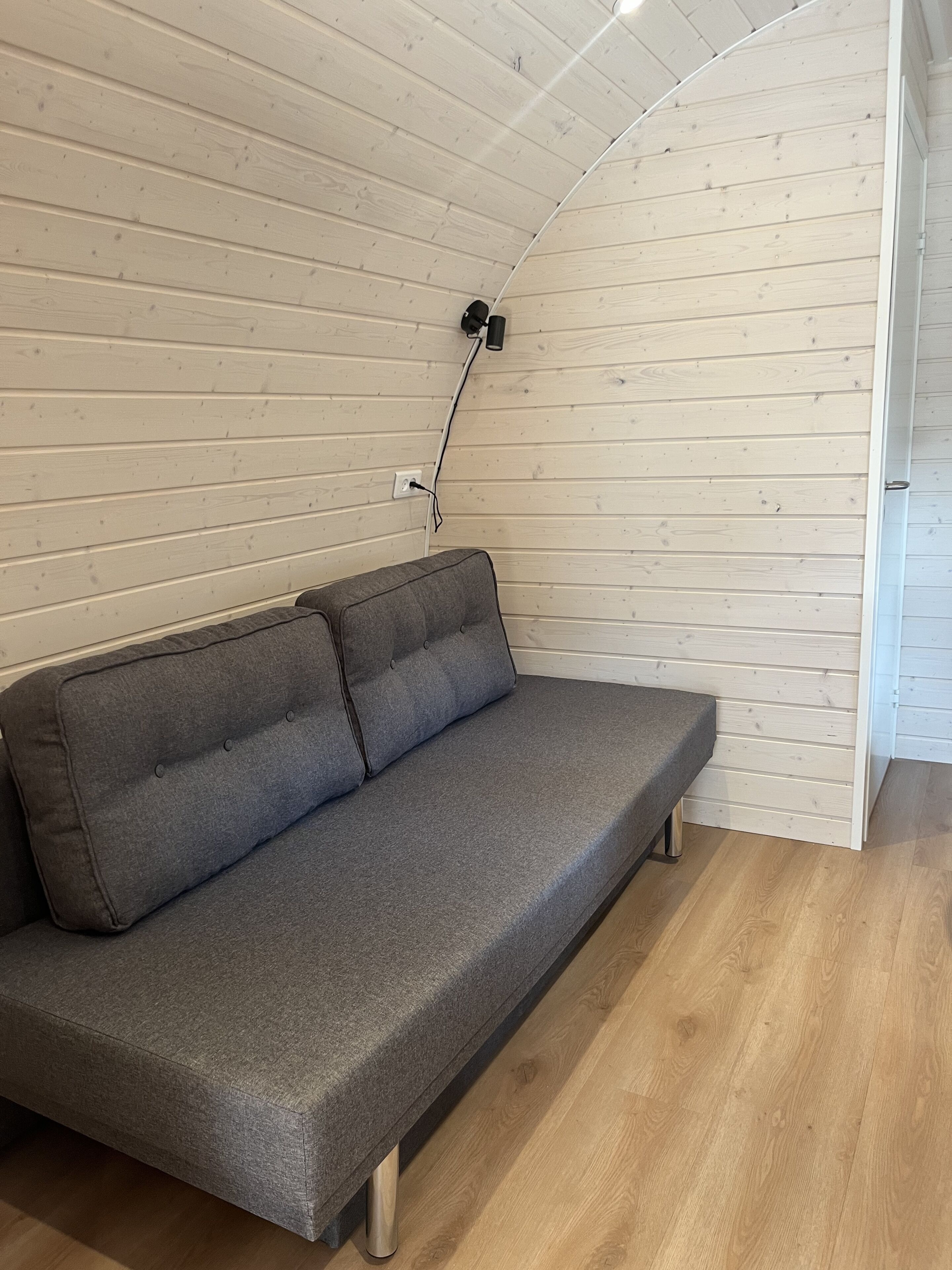 Ein graues Sofa mit Holzboden und einer weißen Holzziel.