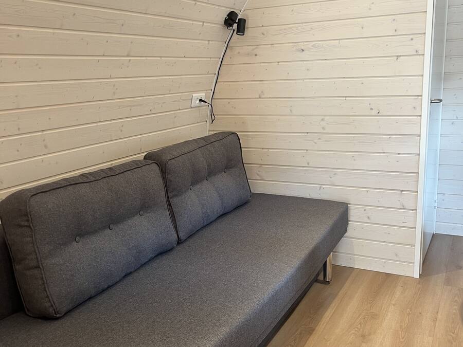A grey sofa with a wooden floor and a white wooden ceiling.