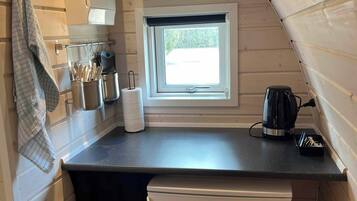 A compact kitchen with a window, a small refrigerator, and a sink.