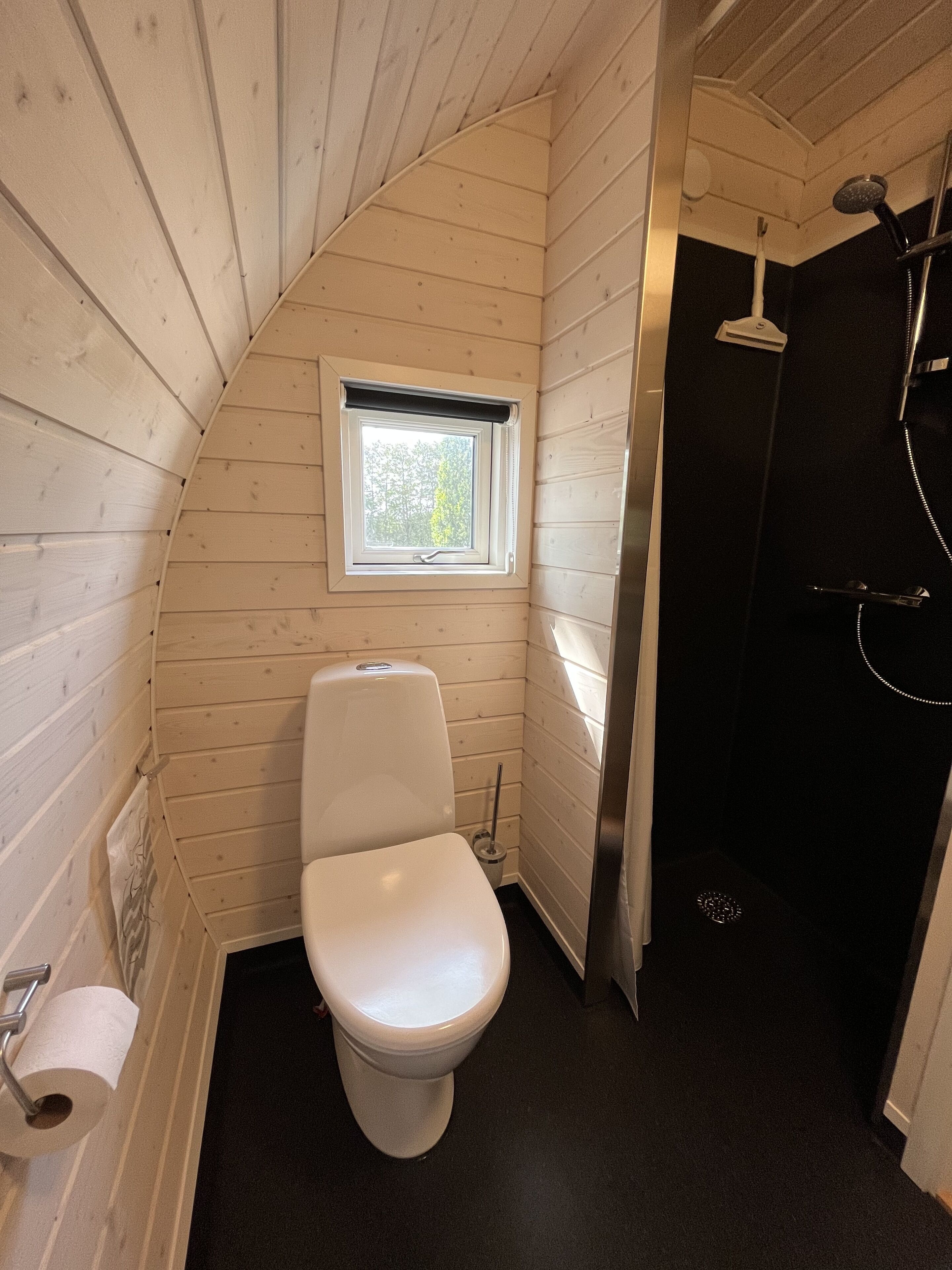Un baño pequeño con inodoro blanco, una ventana y zona de ducha.