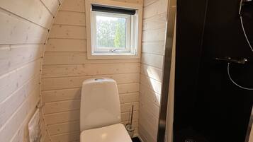 Un baño pequeño con inodoro blanco, una ventana y zona de ducha.