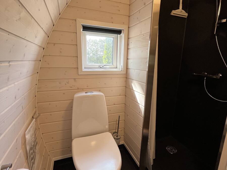 Un baño pequeño con inodoro blanco, una ventana y zona de ducha.