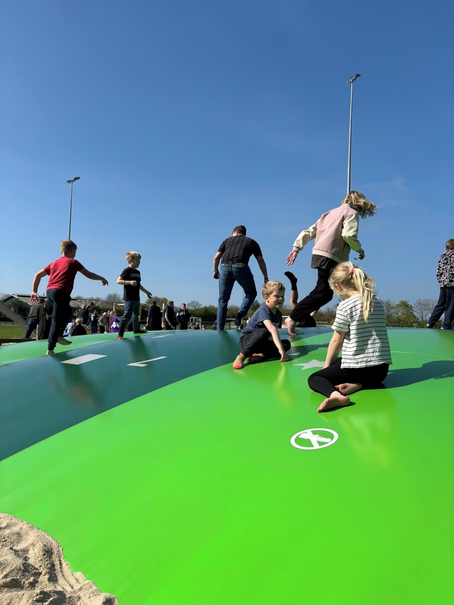 A group of people on a green outdoor surface with a clear sky.