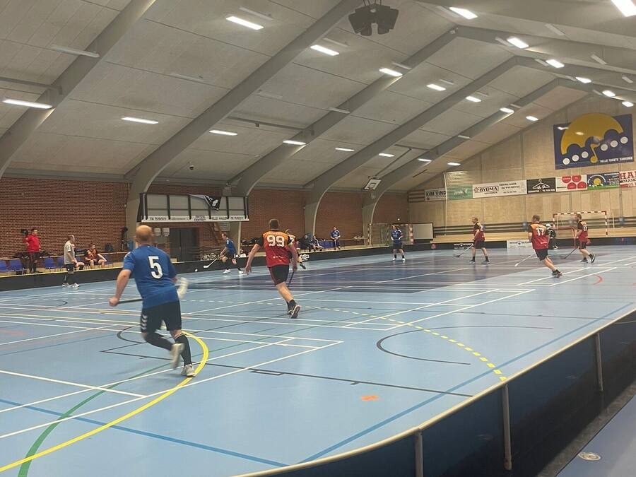 Una cancha cubierta para deportes con diversas actividades, que incluye un aro de baloncesto y una red de voleibol.