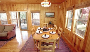 Un intérieur en bois avec une table à manger dressée pour six personnes, entourée de chaises.
