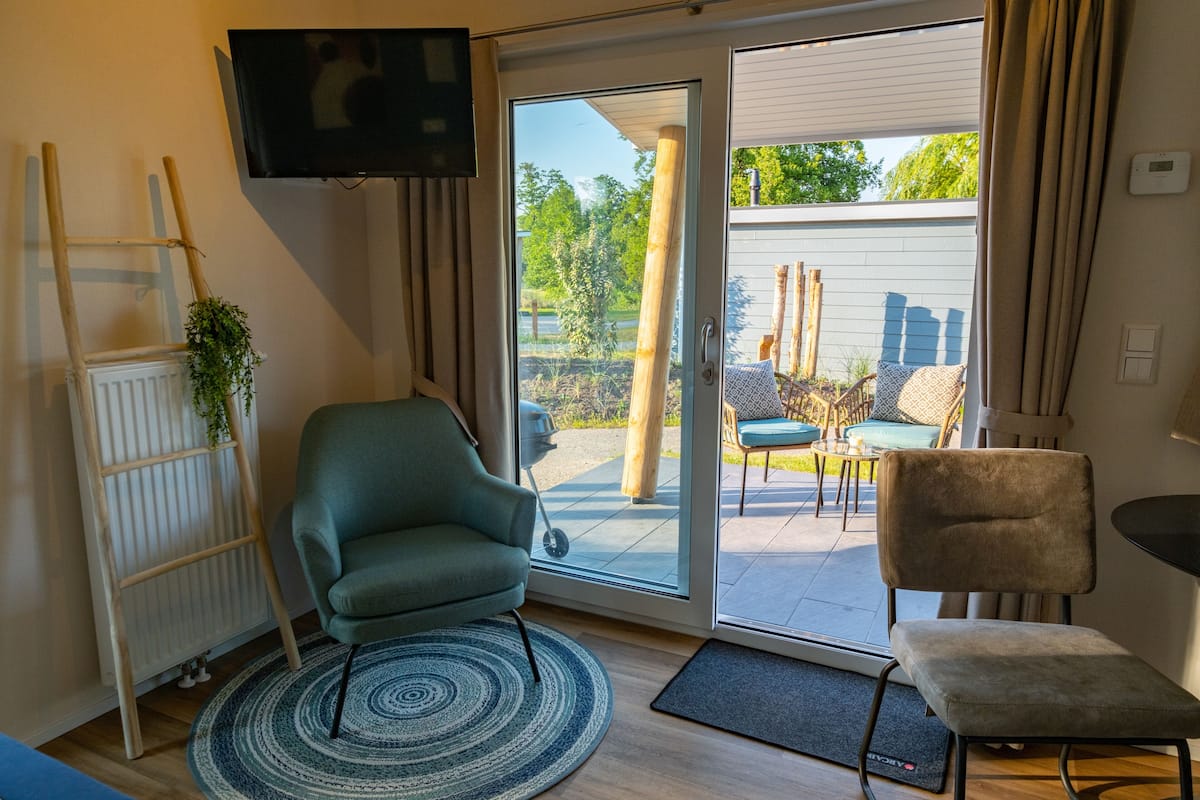 A modern living room with a sofa, a chair, a TV, and a sliding glass door leading to an outdoor patio.