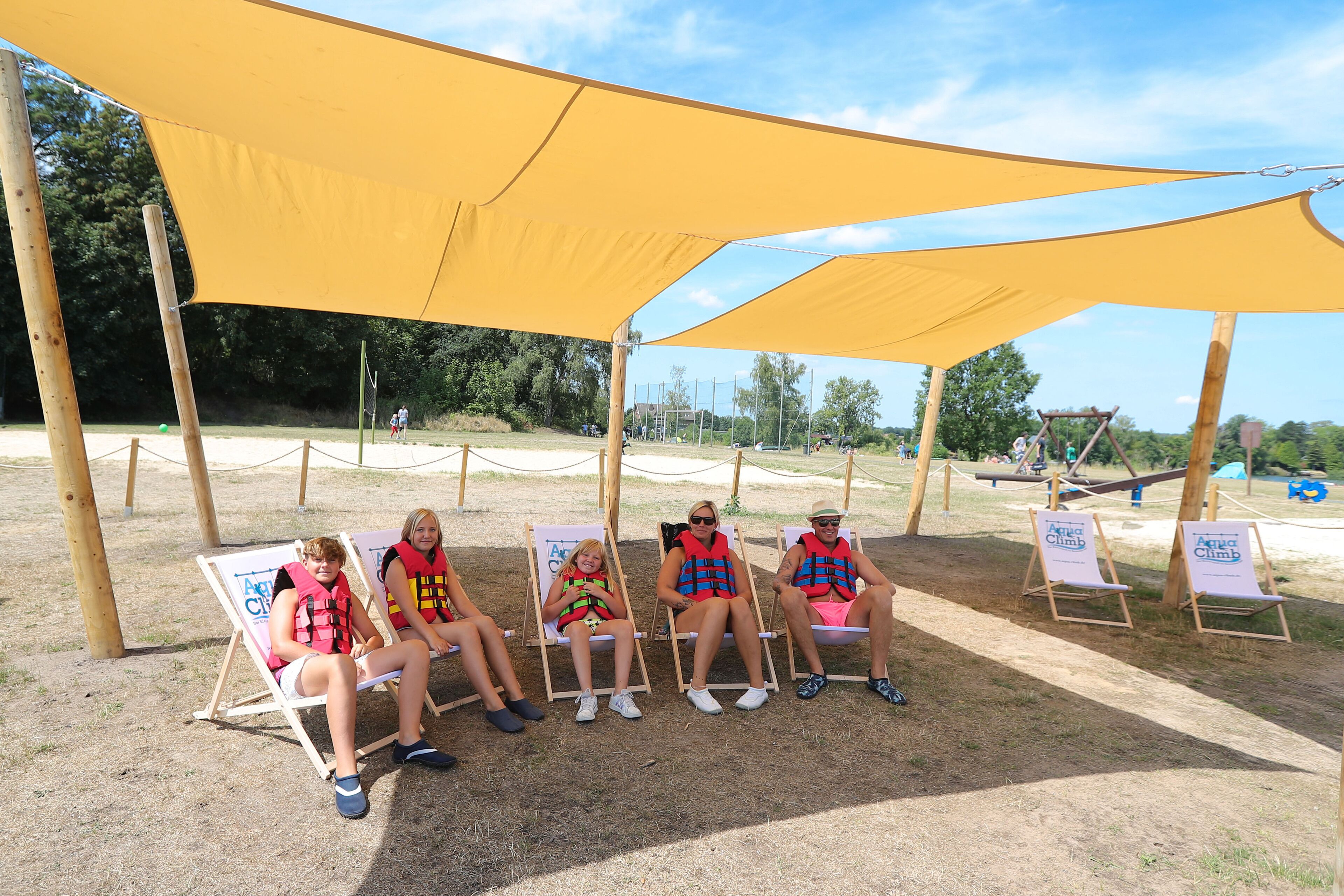 Four people seated under a yellow canopy at an outdoor event.
