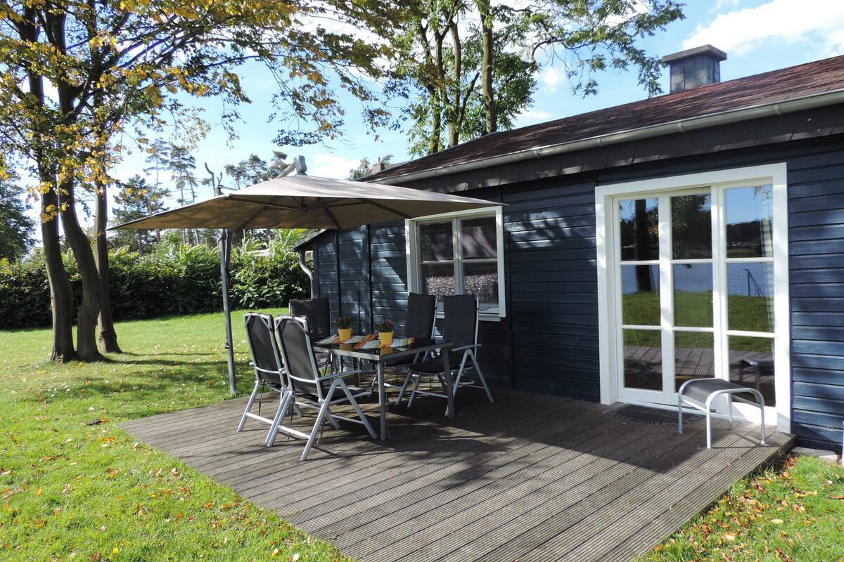 A deck with a table and chairs, a patio umbrella, and a house with a chimney.