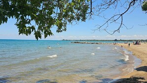 Una playa con agua cristalina, una orilla arenosa y un promontorio rocoso a lo lejos.
