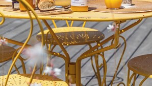 Een tafel met een fles sinaasappelsap, een glas sinaasappelsap, een mand met fruit en een pot honing.