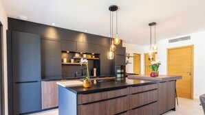 Een moderne keuken met een centraal eiland, donkere kastjes en hanglampen.