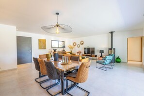 Un espace de salle à manger moderne, doté d’une grande table, de chaises et d’un luminaire suspendu.