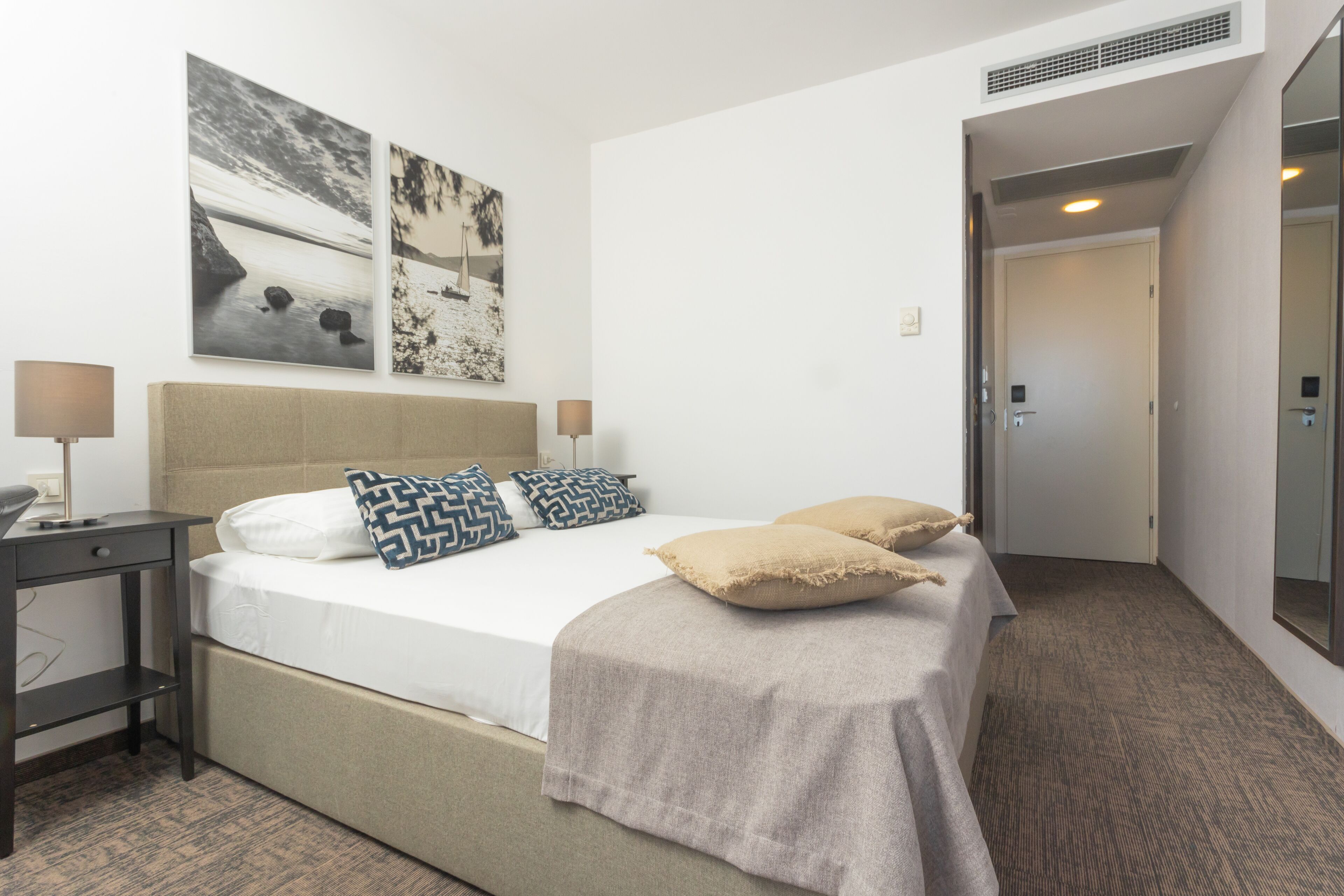 Ein Hotelzimmer mit einem Bett, zwei Nachttischen und einem großen Spiegel.