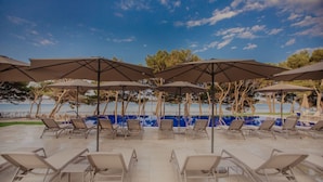 A poolside area with lounge chairs and umbrellas, overlooking a body of water. - Villa Arausa (Vodice)