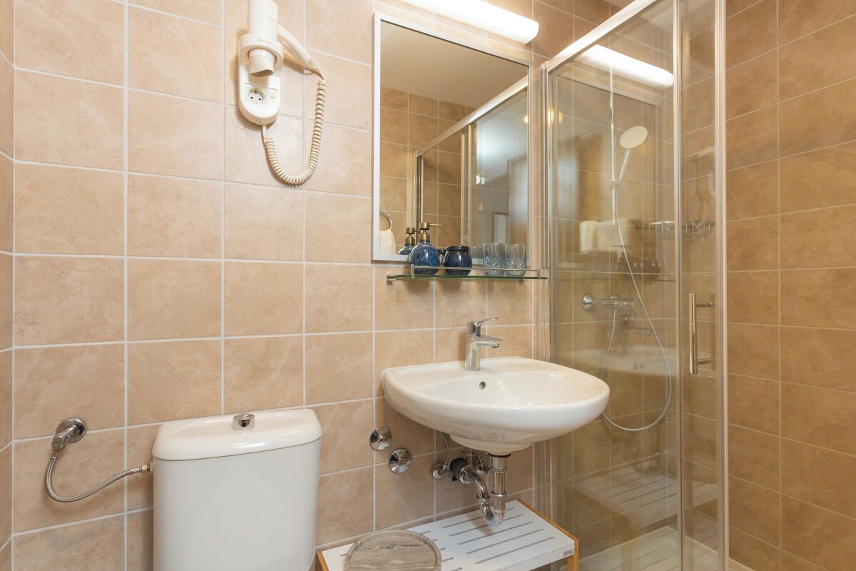 A bathroom with a toilet, sink, and glass shower enclosure.